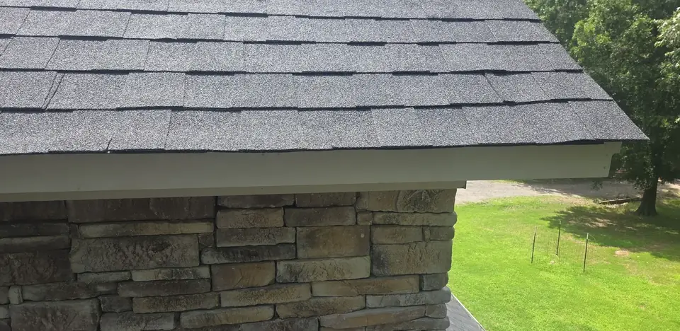 Finished shingle eave and white fascia above a stacked stone wall on a home in Austin