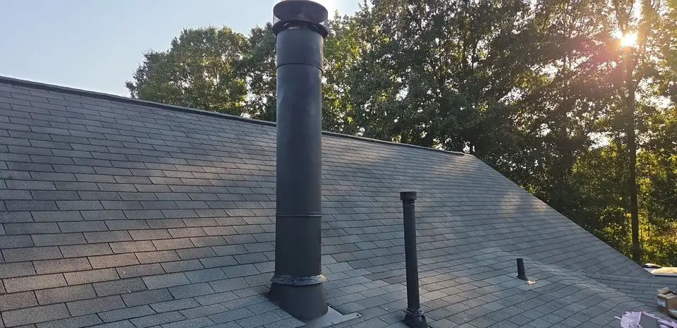 Freshly sealed flue and vent pipe flashing on a shingle roof in Cabot