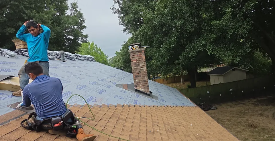 Roofers laying new synthetic underlayment and shingles on a home in Conway