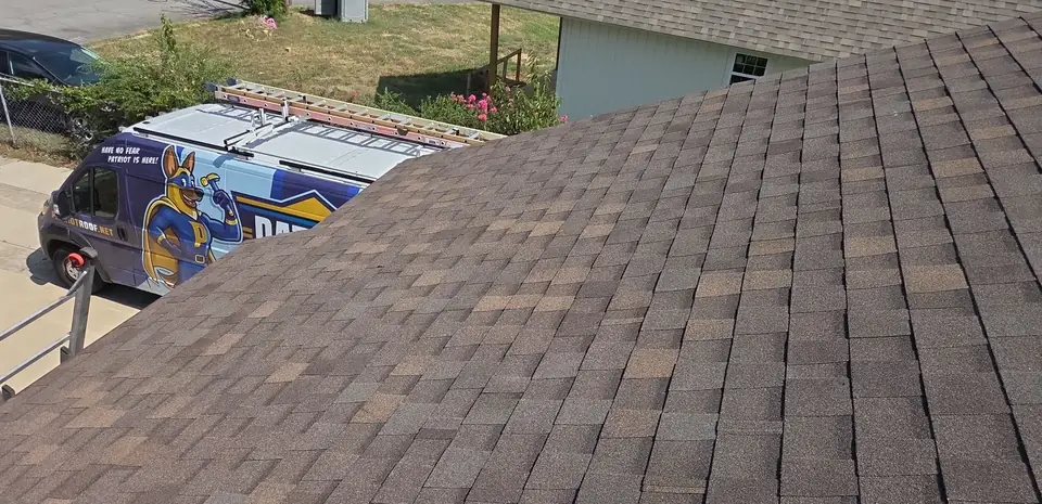 A finished brown architectural shingle roof in Little Rock with a Patriot Roofing van parked below