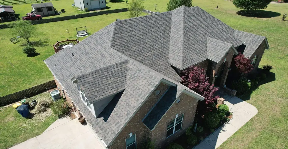 Aerial view of a new shingle roof with dormers on a brick home on a large lot in Scott