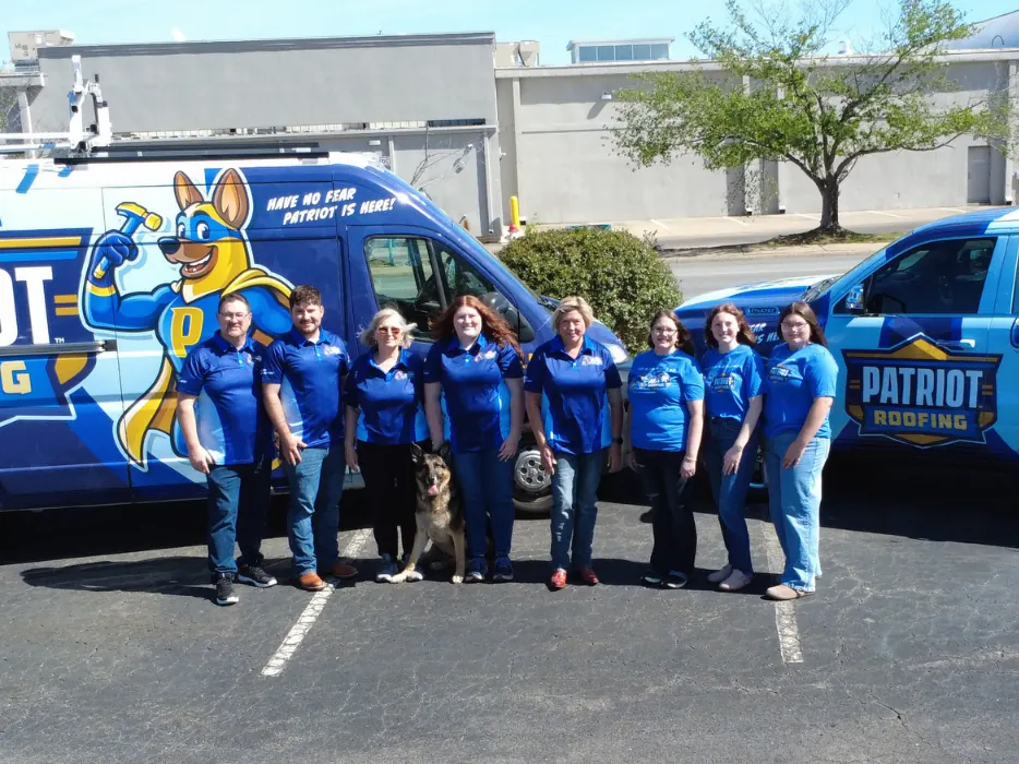 The Patriot Roofing and Restoration team lined up between a wrapped Patriot Roofing and Restoration van and pickup