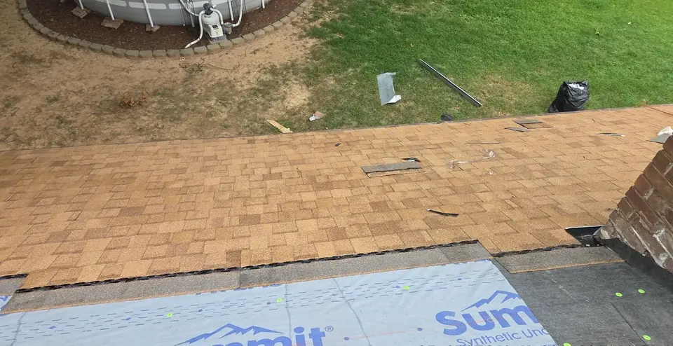 Synthetic underlayment rolled out ahead of new shingles during a roof replacement