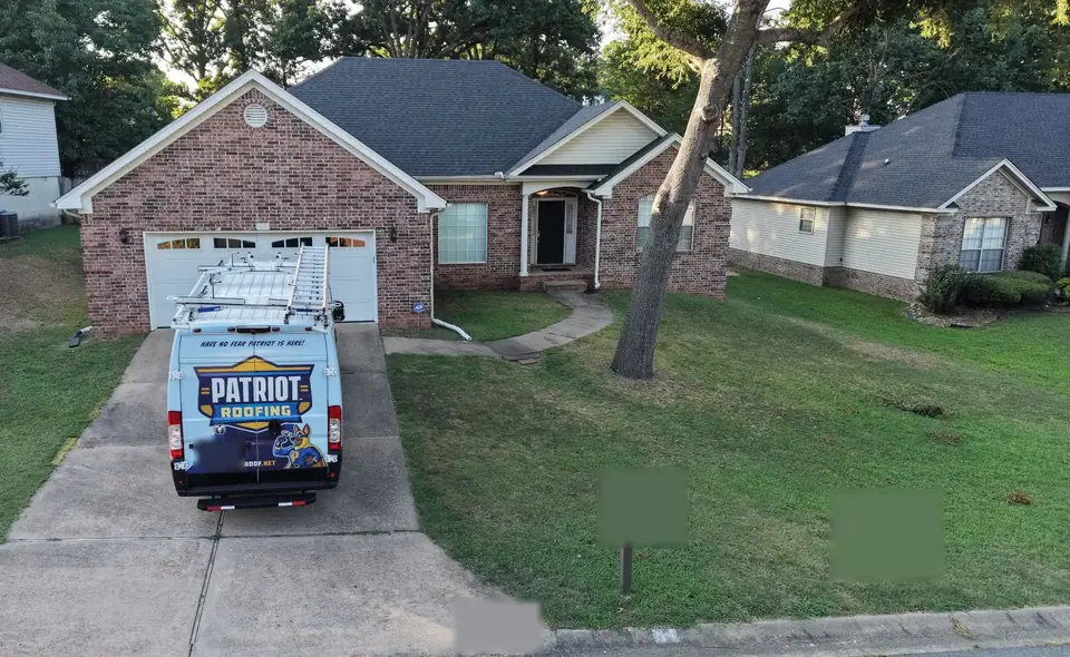 Drone view of a Patriot Roofing van parked in the driveway of a brick home before an inspection