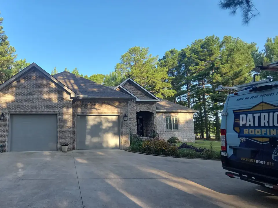 A Patriot Roofing van at a large brick home with a three-car garage in Jacksonville