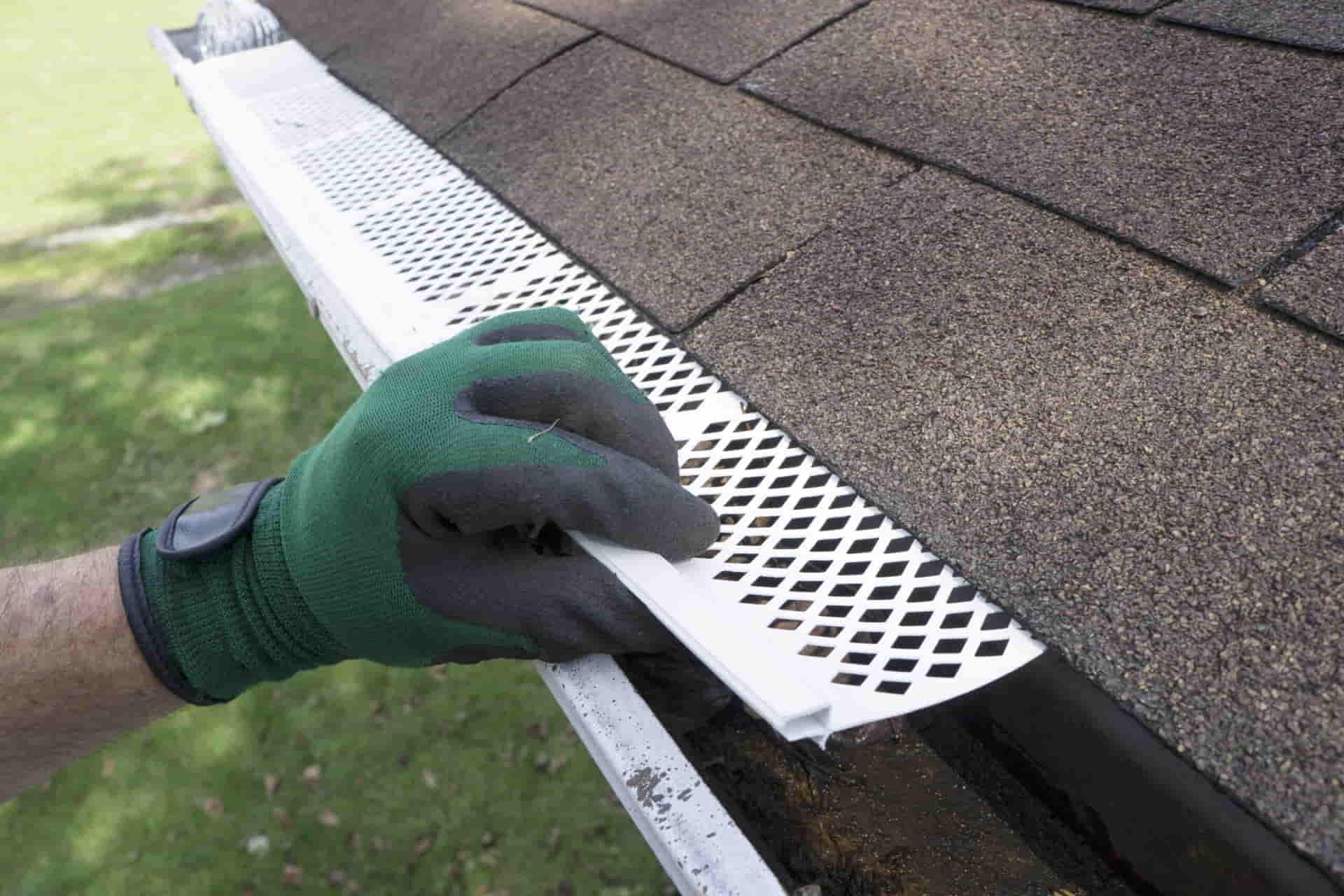 Installer fitting a gutter guard onto a gutter