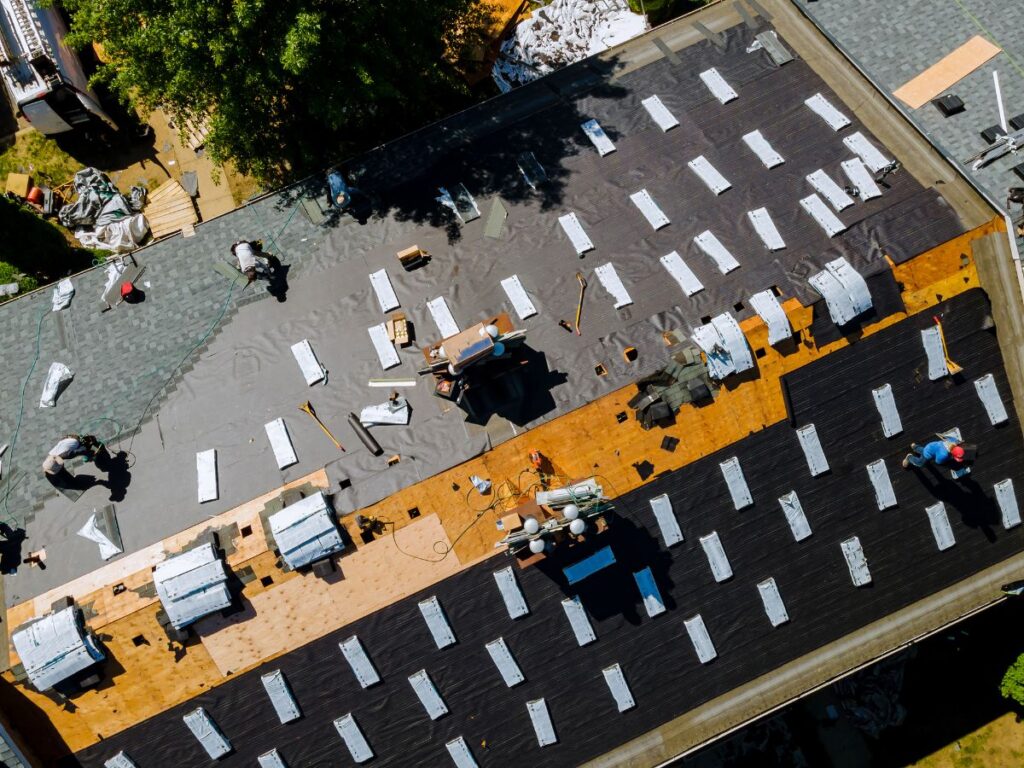 Roofers installing architectural shingles on roof deck