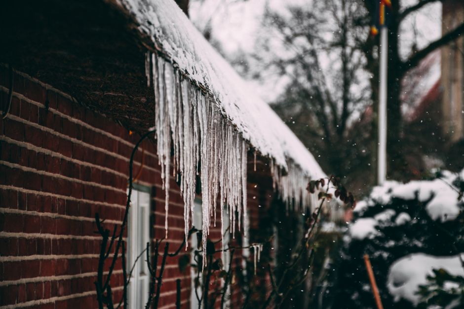 ice dam on Arkansas home roof with icicles hanging from gutters in winter