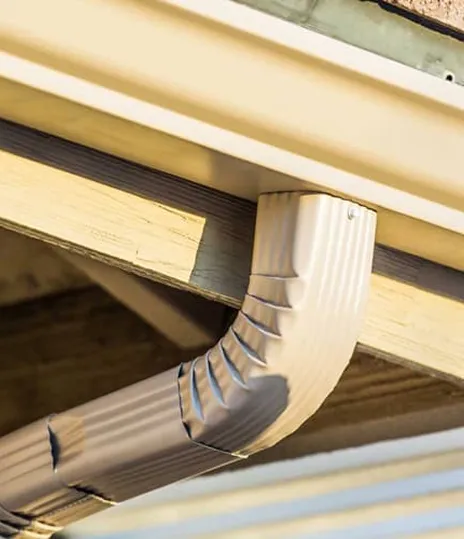 White gutter and downspout against a home exterior