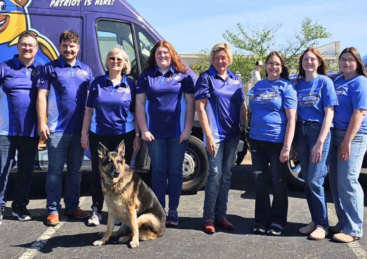 Patriot Roofing team standing with a branded service van