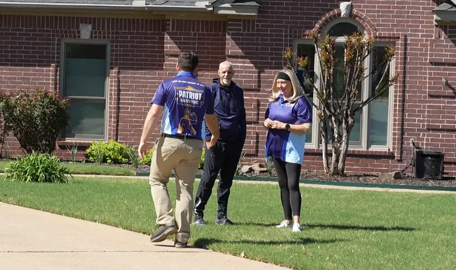 Patriot Roofing team members walking across a lawn in branded shirts