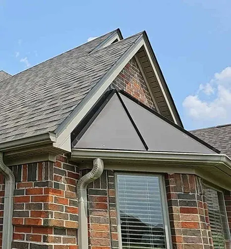Brick home with a shingle roof and mature trees