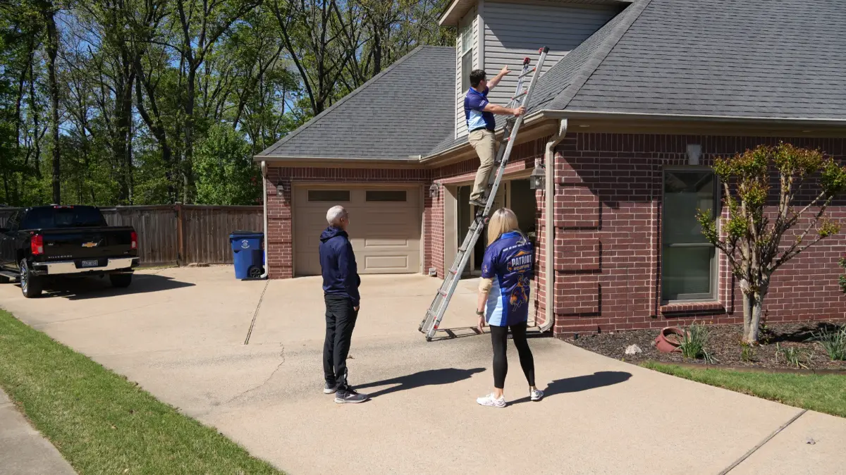 Patriot Roofing crew setting a ladder against a house